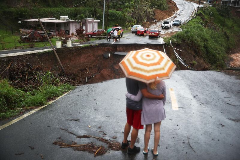 People look on at a section of a road that collapsed and continues to erode days after Hurricane Maria swept through the island in Barranquitas, Puerto Rico. Joe Raedle / Getty Images