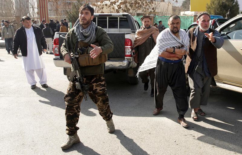 A soldier reacts as a wounded man is assisted at the site of a deadly suicide attack in the center of Kabul. Massoud Hossaini / AP Photo