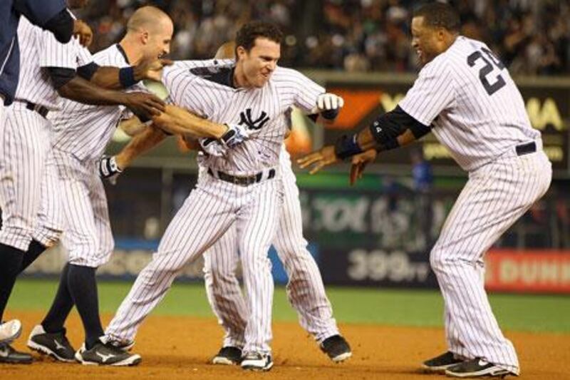 Jayson Nix is mobbed by fellow Yankees after hitting a game-winning single. Mike Stobe / Getty Images / AFP