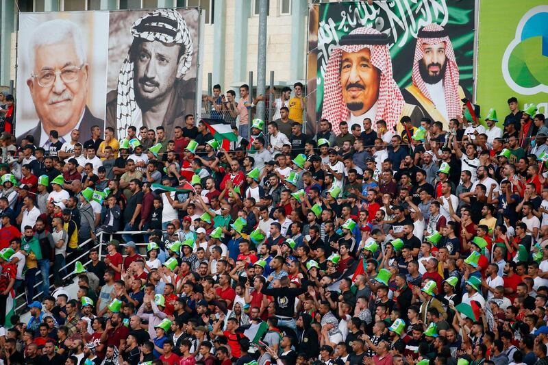 Football fans cheer below a banner bearing the portraits of Palestinian President Mahmud Abbas (L), late Palestinian leader Yasser Arafat (2nd-L), Saudi Arabia's King Salman (2ns-R) and Crown Prince Mohammed bin Salman (R) ahead of the World Cup 2022 Asian qualifying match between Palestine and Saudi Arabia in the town of al-Ram in the Israeli occupied West Bank. The game would mark a change in policy for Saudi Arabia, which has previously played matches against Palestine in third countries. Arab clubs and national teams have historically refused to play in the West Bank, where the Palestinian national team plays, as it required them to apply for Israeli entry permits.  AFP