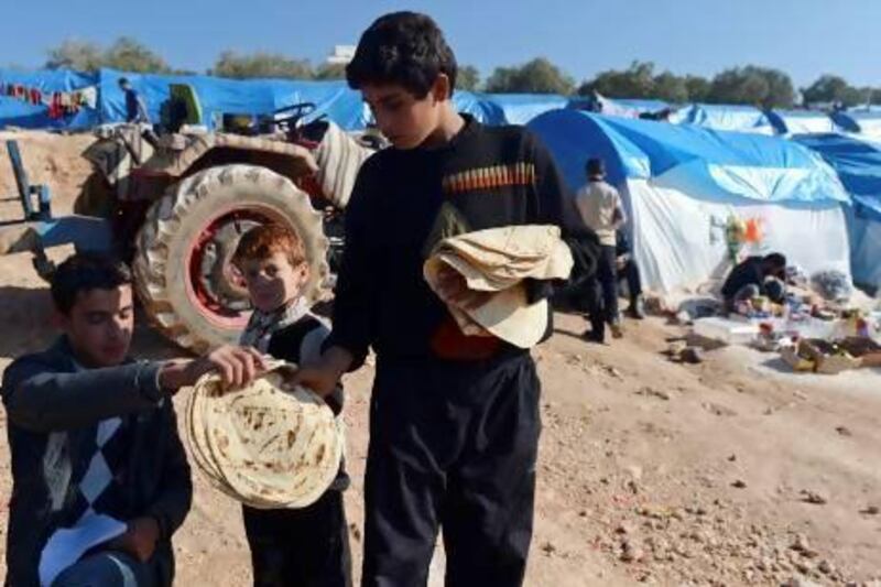 A young Syrian distributes bread in the refugee camp of Qah, in the northwestern Syrian province of Idlib.