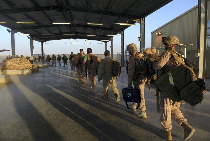 US Marines carry their equipment as British and US troops withdraw from the Camp Bastion-Leatherneck complex at Lashkar Gah in Helmand province on October 26, 2014. British forces on October 26 handed over formal control of their last base in Afghanistan to Afghan forces, ending combat operations in the country after 13 years which cost hundreds of lives. The Union Jack was lowered at Camp Bastion in the southern province of Helmand, while the Stars and Stripes came down at the adjacent Camp Leatherneck -- the last US Marine base in the country. AFP PHOTO / WAKIL KOHSAR (Photo by WAKIL KOHSAR / AFP)