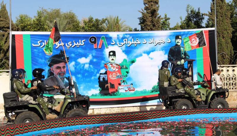 Afghan security officials pass by the picture of former Afghan King Ghazi Amanullah Khan, as they mark the Independence Day in Helmand, Afghanistan. Watan Yar / EPA.