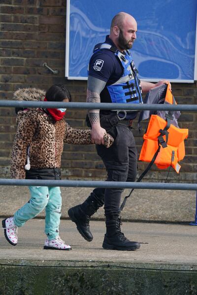 A young girl in pyjamas and a winter coat is led away from a boat in Dover, Kent, on Thursday after arriving from France. PA