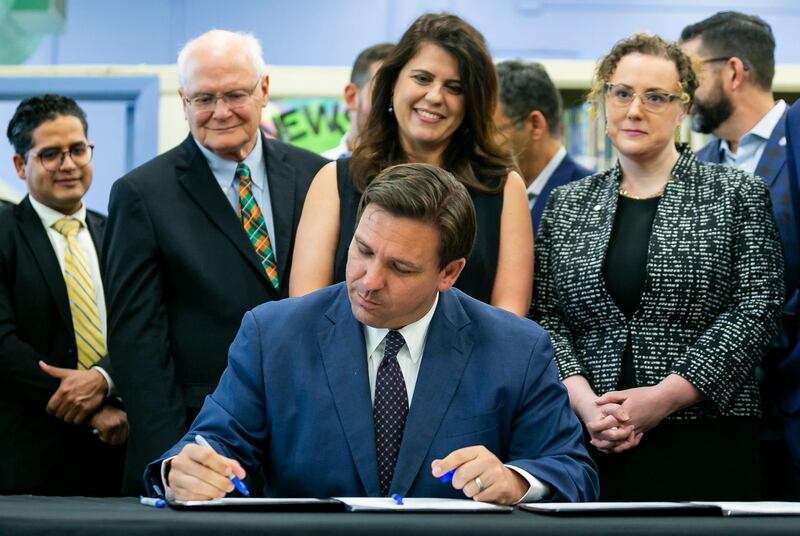 Florida Gov. Ron DeSantis, center, signs bills revamping Florida's literacy and early childhood learning in West Miami Middle School in Miami on Tuesday, May 4, 2021. (Matias J. Ocner/Miami Herald via AP)