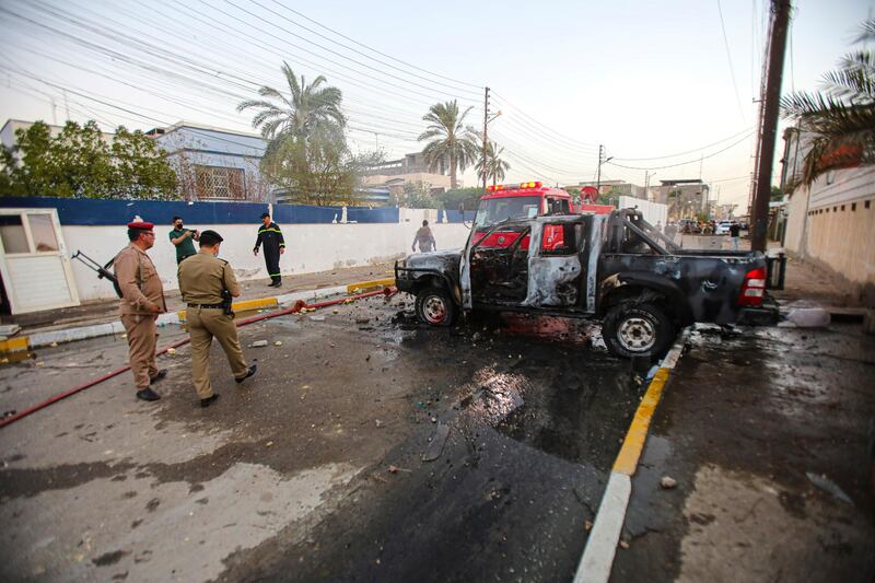 Security forces inspect a burned police vehicle during anti-government protests in Basra, Iraq. AP Photo