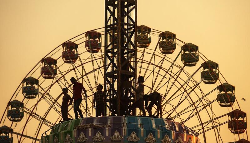 People work in front of a ferris wheel in an amusement park during the annual Mahim Fair in Mumbai, India. Divyakant Solanki/EPA