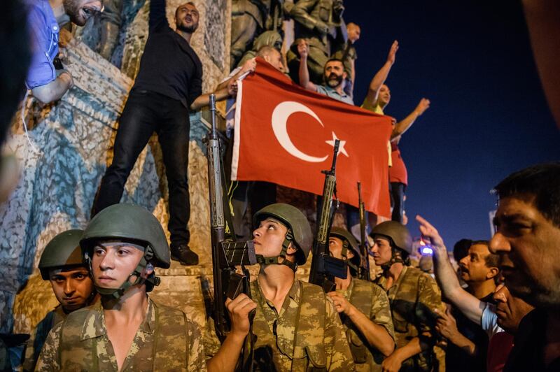 EDITORS NOTE: Graphic content / Turkish solders stay with weapons at Taksim square as people protest against the military coup in Istanbul on July 16, 2016. - Turkish military forces on July 16 opened fire on crowds gathered in Istanbul following a coup attempt, causing casualties, an AFP photographer said. The soldiers opened fire on grounds around the first bridge across the Bosphorus dividing Europe and Asia, said the photographer, who saw wounded people being taken to ambulances. (Photo by OZAN KOSE / AFP)