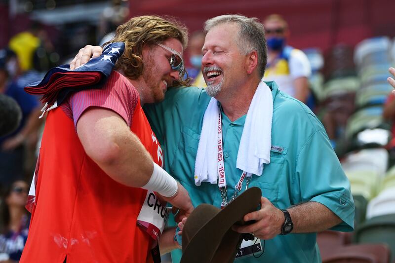 Ryan Crouser, of United States, holds a sign while celebrating winning the gold medal in the final of the men's shot put with his father and coach, Mitch Crouser, at the 2020 Summer Olympics.