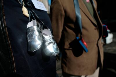 People with baby shoes tied with black ribbons hanging from their neck, symbolizing the children who died in "mother and baby homes", the homes where children were exiled for the shame of having been born to unwed mothers, protest in Dublin ahead of the visit of Pope Francis, in Dublin, Ireland, Saturday, Aug. 25, 2018 . The pontiff is traveling to Ireland for a two-day visit. (Aaron Chown/PA via AP)