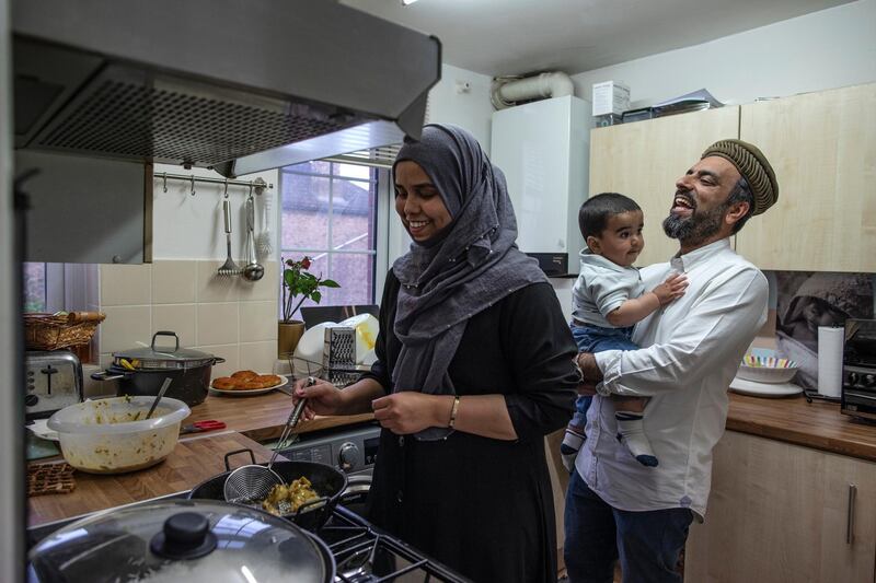 LONDON, ENGLAND - MAY 08: Imam Raza Ahmed holds his son Daud as his wife Anam prepares food for iftar at their family home on May 08, 2020 in London, England. Ramadan is the ninth month of the Islamic calendar and the month in which the Quran was revealed to the prophet Muhammad. It is a time when Muslims around the world observe their faith with a month-long ritual of fasting and prayer, before making way for the holiday of Eid. With the coronavirus pandemic still at large and lockdowns still in place, close-knit religious communities have had to adapt to a new reality. Where once large gatherings at mosques every evening to break fast in the company of friends were commonplace, simpler home cooked meals in the company of immediate family are the new norm. The UK is continuing with quarantine measures intended to curb the spread of Covid-19, but as the infection rate is falling, government officials are discussing the terms under which it would ease the lockdown. (Photo by Dan Kitwood/Getty Images)