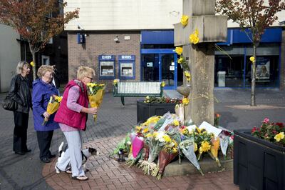 Women prepare to place a floral tribute at the base of the Eccles Cross for murdered aid worker Alan Henning in Eccles, north west England on October 5, 2014. Britain united in revulsion Saturday at the beheading of aid worker Alan Henning claimed by Islamic State jihadists, as the imam at his home city's main mosque hailed a "local and national hero". Prime Minister David Cameron led tributes to the 47-year-old taxi driver who went to the region as a volunteer to deliver aid and whose death was announced by Islamic State jihadists in a video released late Friday, October 3, 2014. AFP PHOTO / OLI SCARFF (Photo by OLI SCARFF / AFP)