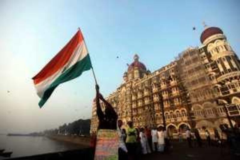 A man waves an Indian flag outside the Taj Mahal hotel, one of the sites of Mumbai terror attacks, on the first anniversary of the attacks in Mumbai, India, Thursday, Nov. 26, 2009. Ahead of Thursday's first anniversary of the deadly terror attacks that paralyzed Mumbai for 60 terrifying hours, groups around the city held vigils, calling for police reform and painting murals to remember the 166 killed. The placard suggests that the man has traveled across the country and reads "Let my country be free from terrorism and corruption." (AP Photo/Rafiq Maqbool)  *** Local Caption ***  DEL105_India_Terror_Anniversary.jpg *** Local Caption ***  DEL105_India_Terror_Anniversary.jpg