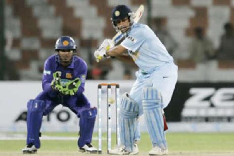 The India captain Mahendra Dhoni prepares to play a shot as the Sri Lankan wicketkeeper Kumar Sangakkara looks on.