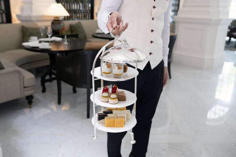 A waiter holds a high tea set for a photograph in the Grand Lobby restaurant at the Raffles Hotel. Bloomberg