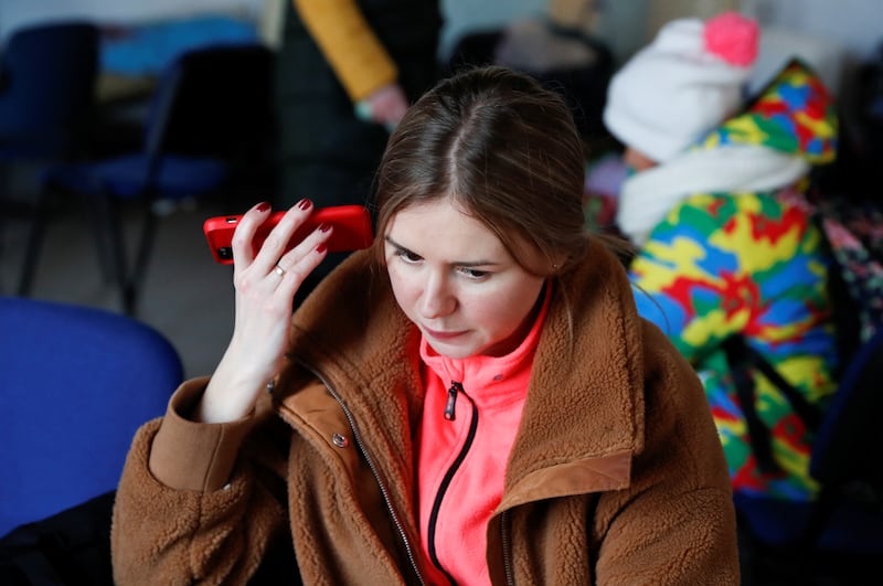 A woman from Ukraine uses a phone to listen to a speech by President Volodymyr Zelenskyy at a refugee shelter in Beregsurany, Hungary. Reuters