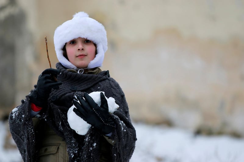 A girl carries a snow ball while playing in Aleppo January 11, 2015. A storm buffeted the Middle East with blizzards, rain and strong winds, keeping people at home across much of the region and raising concerns for Syrian refugees facing freezing temperatures in flimsy shelters. The storm is forecast to last several days, threatening further disruption in Lebanon, Syria, Turkey, Jordan, Israel, the West Bank and the Gaza Strip, which have all been affected REUTERS/Hamid Khatib (SYRIA - Tags: SOCIETY ENVIRONMENT)