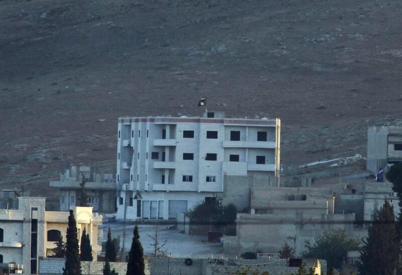 In this image shot with an extreme telephoto lens from the outskirts of Suruc at the Turkey-Syria border, ISIL's trademark black flag is seen atop of a building at the eastern end of the town of Kobani, Syria, on Monday. Lefteris Pitarakis / AP Photo