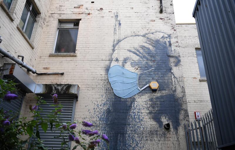 British artist Banksy's work 'Girl with a Pierced Eardrum' is displayed wearing a mask in Bristol, UK.  EPA