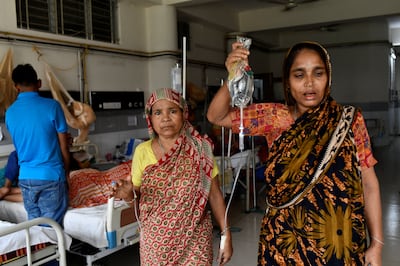 An assistant holds a drip for a patient with dengue fever at a hospital in Dhaka, Bangladesh. Reuters