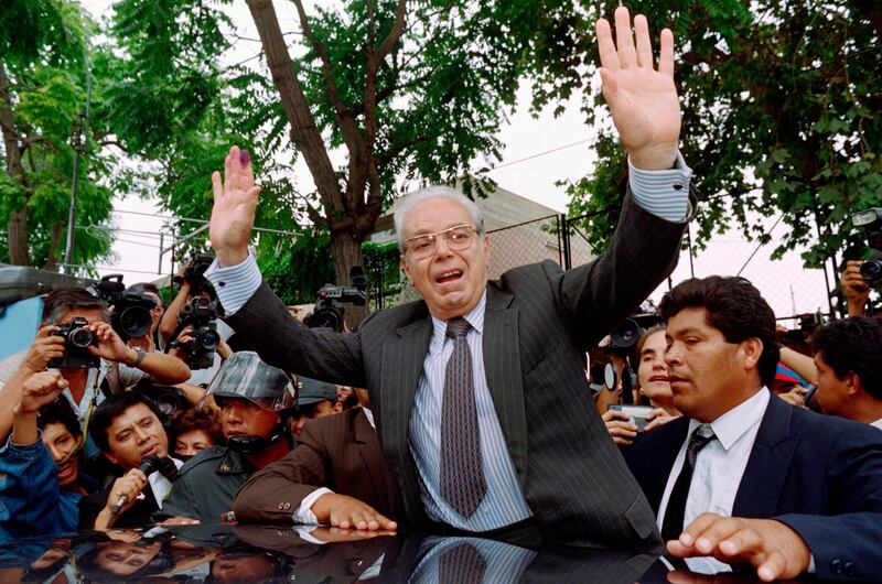 Mr de Cuellar waves to cheering supporters outside a local polling station shortly after voting in the Peruvian General elections in Lima in 1995. AFP