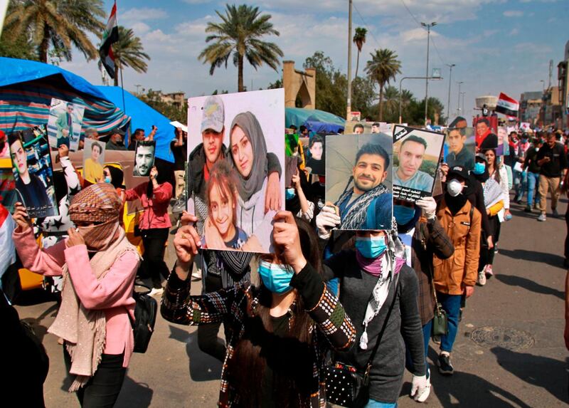 Anti-government protesters hold pictures of protesters who have been killed in anti-government demonstrations, during a rally in Baghdad, Iraq. AP Photo