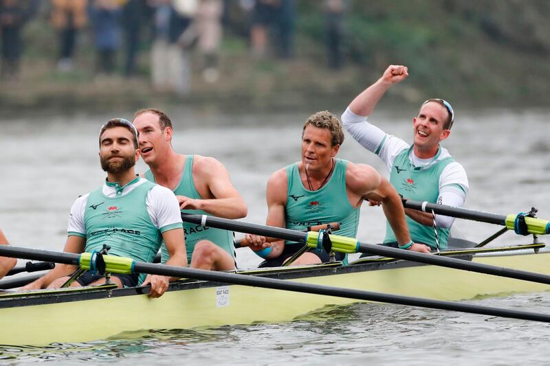 (L-R) Bermudian/British/US/Iranian rower Dara Alizadeh, US rower Grant Bitler, British rower James Cracknell and British rower Dave Bell in the Cambridge boat celebrate their win at the finish line after the 165th annual men's boat race between Oxford University and Cambridge University on the River Thames in London on April 7, 2019.   / AFP / Tolga AKMEN
