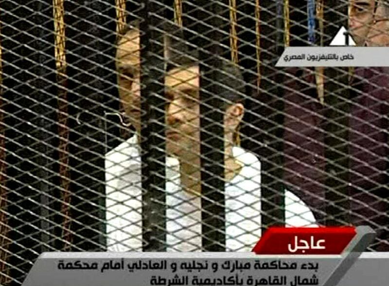 This video image taken from Egyptian State Television shows Gamal, left, and Alaa Mubarak, right in white prison uniforms, the two sons of Hosni Mubarak, in a cage of mesh and iron bars in a Cairo courtroom Wednesday Aug. 3, 2011. An ailing, 83-year-old Hosni Mubarak lay on a hospital bed inside a cage of mesh and iron bars in a Cairo courtroom Wednesday as his historic trial began on charges of corruption and ordering the killing of protesters during the uprising that ousted him. The scene, shown live on Egypt's state TV, was Egyptians' first look at their former president since Feb. 10, the day before his fall when he gave a defiant speech refusing to resign.   (AP Photo/Egyptian State TV)   EGYPT OUT *** Local Caption ***  Egypt Mubarak Trial.JPEG-0c1d4.jpg