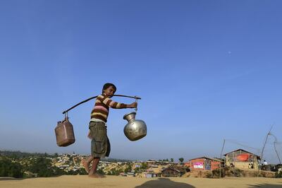 TOPSHOT - A Rohingya refugee child walks back to his makeshift shelter after collecting water at Hakimpara refugee camp in Bangladesh's Ukhia district on January 27, 2018.
The repatriation of hundreds of thousands of Rohingya Muslims who fled violence in Myanmar will not begin as planned, Bangladesh said January 22, with authorities admitting "a lot of preparation" was still needed. / AFP PHOTO / Munir UZ ZAMAN