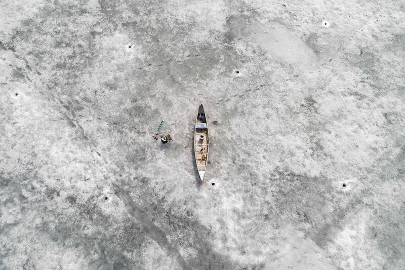 This aerial picture taken from a drone shows a canoe lying on the ice, near holes made by fishermen  in Bjoerkoe, Raipaluoto Island, western Finland. Olivier Morin / AFP