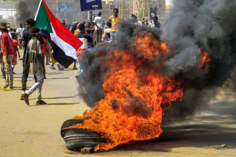 Protesters walk past burning tyres during an anti-military demonstration in Sudan's capital Khartoum. AFP