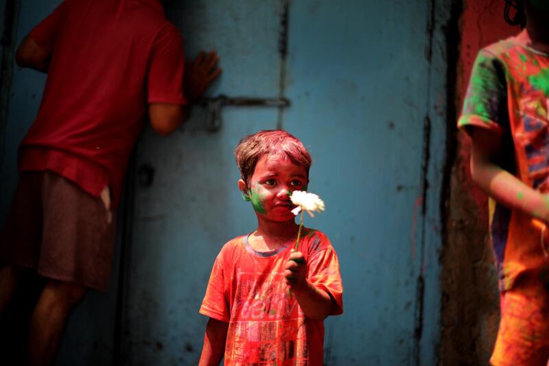 A child covered in colour dust stands as tourists and locals celebrate the Hindu festival of Holi in Kolkata, in eastern India, on March 28, 2021. EPA