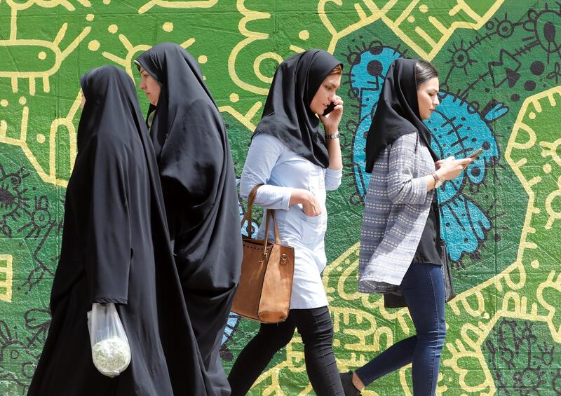 epa06698527 Iranians walk past a wall painting while using the cellphones in a street, in Tehran, Iran, 28 April 2018. Iranian government officially lunched home-made app 'Soroush' with list of emojis in the form of little veiled women with special political messages. The new app was released to replace the popular messaging service Telegram, which was reportedly banned in the county after it was extensively used in communications during the 2017 anti-government protests.  EPA/ABEDIN TAHERKENAREH