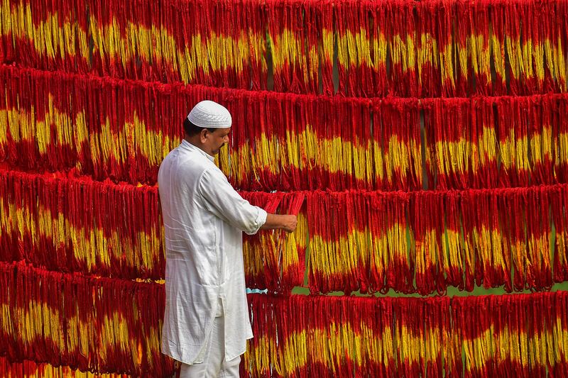 A workshop owner checks freshly-dyed Kalawa threads, a traditional sacred orange-yellow thread used in Hindu rituals, ahead of the Navratri festival at Lalgopalganj village, 45km from Allahabad. AFP