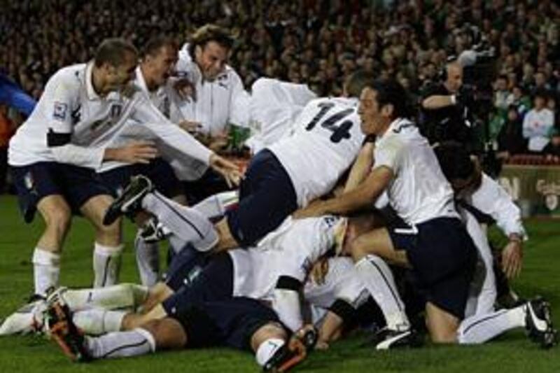 Italy's players pile on top of Alberto Gilardino, whose last-minute equaliser against Irerland in Dublin saw them qualify for the World Cup.