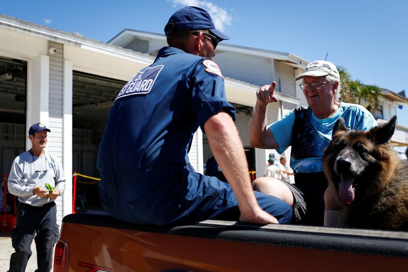 Andy Sherwood talks with a US Coast Guard officer as he is being evacuated from the island with his dog. Reuters