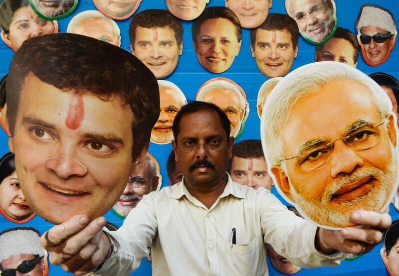 A shopkeeper poses as he holds masks of Indian Congress Party President Rahul Gandhi and Indian Prime Minister Narendra Modi displayed for sale at a roadside shop in Chennai on March 14, 2019. India is not just the world's biggest democracy, its elections are also the most gruelling -- with nearly six weeks between the first round of voting on April 11 and the last. / AFP / ARUN SANKAR
