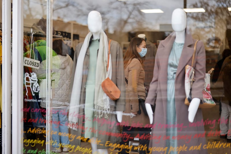 A shopper wearing a face covering browses clothes in a charity shop in north London. AFP