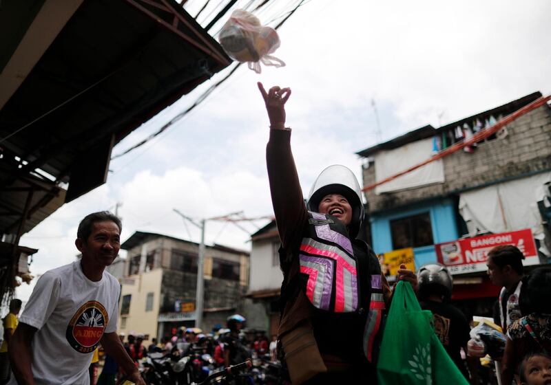 A Filipino motorcycle rider tosses a bag of goods during an aid mission in Marikina.  EPA