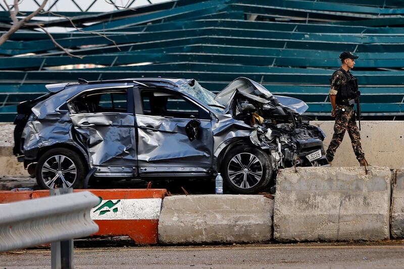 A soldier walks past a damaged car at the site of last week's explosion in Beirut, Lebanon. AP Photo