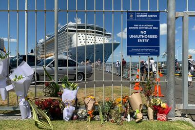 Flowers are laid on makeshift memorial is seen in front of cruise ship Ovation of the Seas, in Tauranga, New Zealand, Tuesday, Dec. 10, 2019. A volcanic island in New Zealand erupted Monday Dec. 9 in a tower of ash and steam while dozens of tourists were exploring the moon-like surface, killing multiple people and leaving many more missing.(AP Photo/Nick Perry)