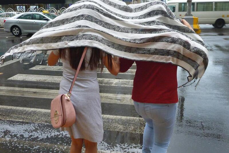 An unexpected shower had these two women using a scarf to cover themselves from the rain. Delores Johnson / The National