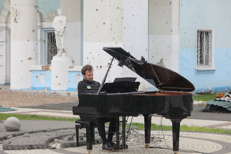 Lithuanian musician Darius Mazintas plays a piano in front of the Central House of Culture, destroyed during Russia's invasion, in the town of Irpin on April 26. Reuters