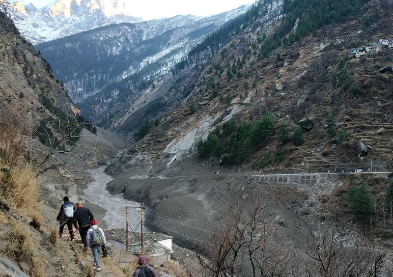 People walk past a destroyed dam after a glacier collapsed and crashed into the dam at Raini Chak Lata village in the Chamoli district. Reuters