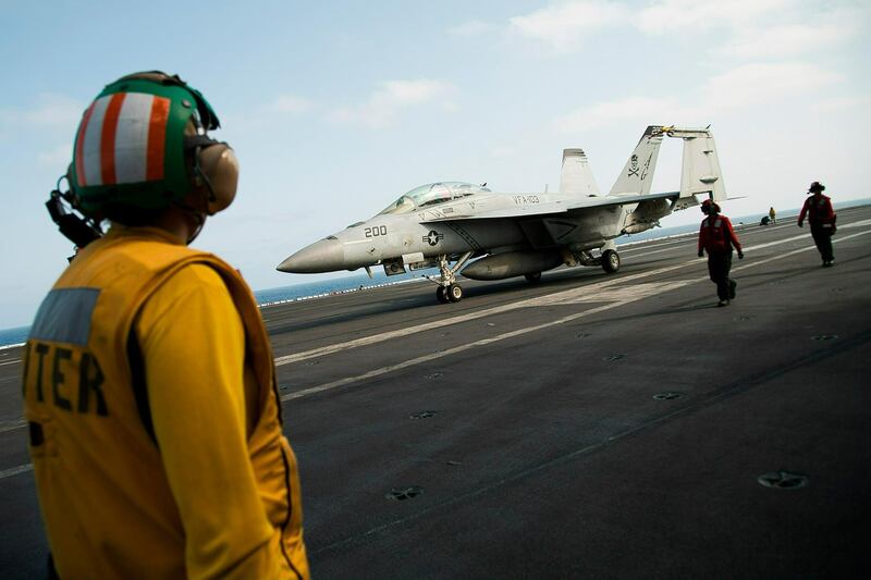 A crew member looks at an F/A-18 fighter jet on the deck of the USS Abraham Lincoln aircraft carrier in the Arabian Gulf. AP Photo