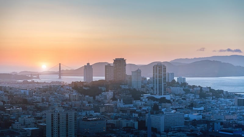 Beautiful colorful sunset over San Francisco Financial District. Sun going down behind the Golden Gate Bridge. Aerial Panoramic View. San Francisco, California, USA.