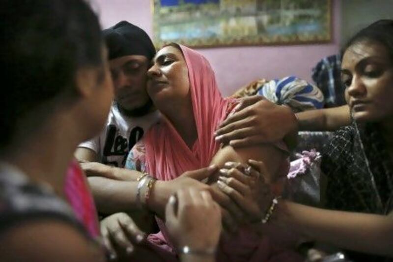 Surinder Kaur, centre, the wife of Seeta Singh who was killed in the shooting attack at a Sikh temple in Wisconsin, is comforted by her son Armeet and daughter Sarabjit, right, at the family home in New Delhi.