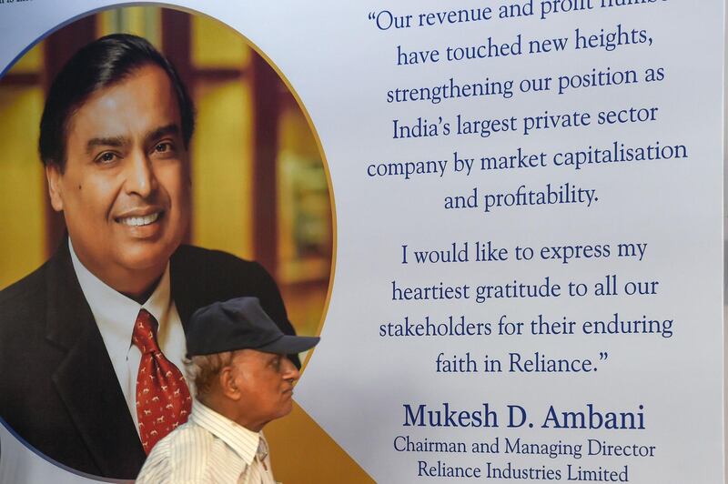 A shareholder walks past a poster of India's richest man and oil-to-telecom conglomerate Reliance Industries chairman Mukesh Ambani at the company's 42nd AGM in Mumbai on August 12, 2019.   / AFP / Indranil MUKHERJEE
