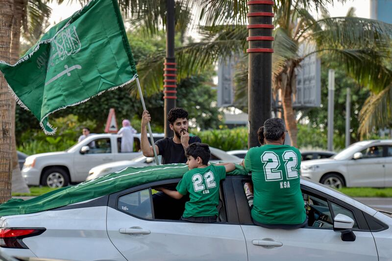 A Saudi football fan waves their country's flag from the window of a car in Riyadh while celebrating after the Qatar 2022 World Cup Group C football match between Argentina and Saudi Arabia on November 22, 2022.  (Photo by AFP)
