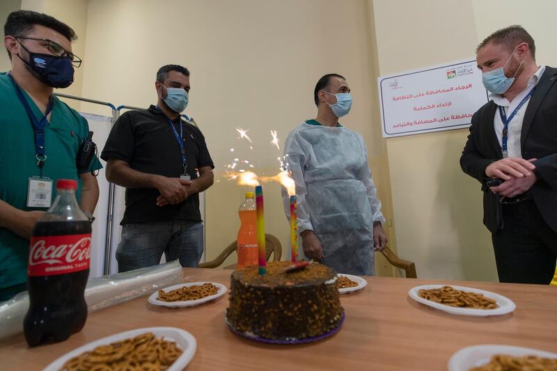 Dr. Moatasem Muheisen, right and his staff throw a birthday party for their colleague Dr. Abdulbaset Zieneddin, 42, second right, in a COVID-19 testing center, at the Ramallah Recreational Complex, in the West Bank city of Ramallah. The Palestinian ministry of health transformed a sports facility into a COVID-19 testing center where health care workers provide support for residents who come forward for a consultation or a COVID-19 test during the pandemic. AP Photo